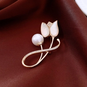 Close-up of 14K gold plated tulip brooch with mother of pearl and pearls on red silk
