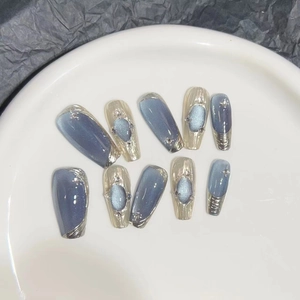 Cat eye press-on nails in deep blue and gold with rhinestone accents and glitter finish