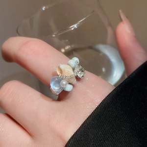 Detailed shot of ocean-style ring featuring seashells, blue beads, and white pearls