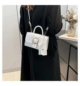 Detail of white crocodile texture handbag featuring a bold gold square buckle and mini pouch