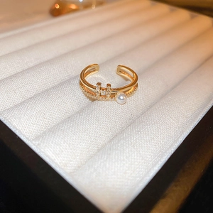 Detail of gold-plated H-letter ring with sparkling zircons on white velvet box