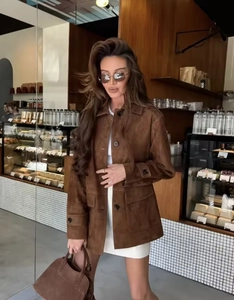 Detail of brown suede utility jacket with functional pockets in a modern cafe setting