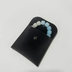 Detail of a black velvet jewelry pouch with snap closure holding a beaded bracelet