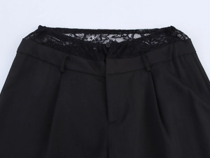Detail of elegant black dress pants featuring intricate lace splicing at the waistline