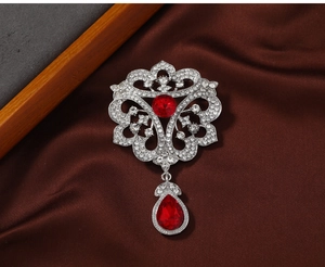 Detail of vintage palace style brooch with silver filigree and red teardrop crystals