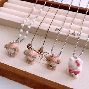 Detail of plush puppy pendant necklace with pearls and saturn orbital charm