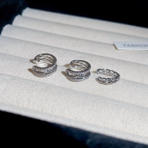 Detailed close-up of three sparkling zircon ear cuffs on a soft beige velvet jewelry tray