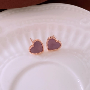 Detailed top view of purple heart earrings with rose gold beaded edges on ceramic tray