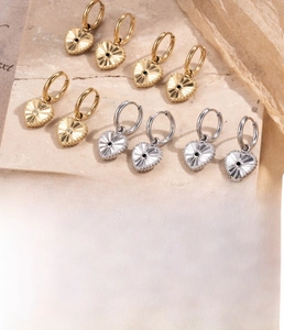 Detail von herzförmigen Ohrringen in Gold und Silber mit Zirkonia auf Steinoberfläche