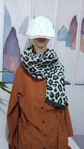 Detail showing white beret and black-white leopard print scarf on model neck