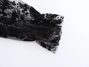 Detailed view of sheer black mesh cuff featuring floral flocking and ruffled lantern sleeve