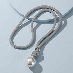 Close-up of woven metallic cord necklace with large white pearl and silver sphere detail
