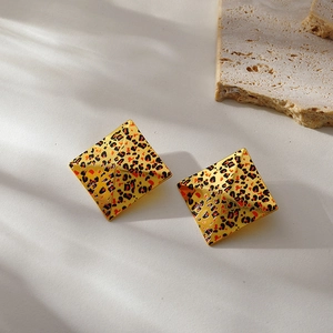 Detailed view of square 18k gold leopard print earrings on a natural stone base