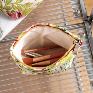 Detail view of pink floral canvas makeup bag with gold zipper and makeup brushes inside