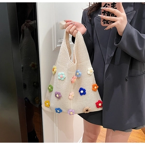 Close-up of cream knit tote bag featuring colorful 3D floral textures and handwoven patterns