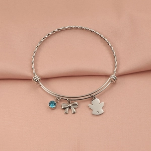 Silver twist wire bracelet with blue gemstone, bow, and angel charms on pink satin
