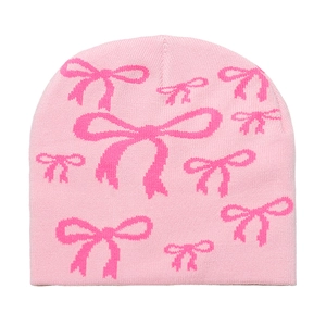 Detailed close-up of pink knit beanie featuring intricate dark pink bow jacquard patterns