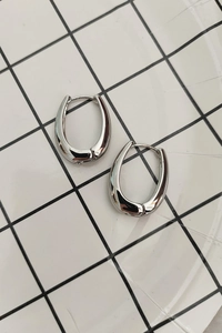 Macro detail of silver U-shaped geometric hoop earrings on checkered background