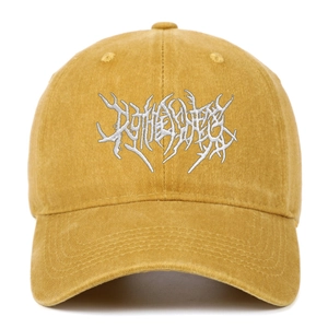 Close-up of white gothic embroidery on vintage washed yellow cotton baseball cap