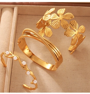Detail of 18K gold-plated bracelets featuring flower patterns and pearl accents on tray
