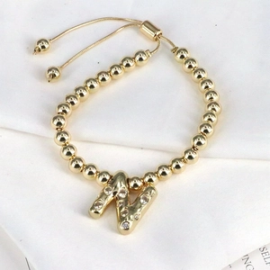Detail of adjustable gold bead bracelet featuring a sparkling zircon letter N pendant