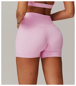 Rear view of high waist yoga shorts in pale pink featuring side pockets and bodycon fit
