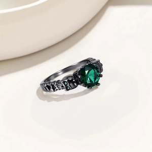 Macro shot of gothic black metal ring with a round green gemstone and skull side details