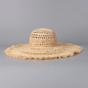 Detail of hollow woven raffia sun hat with wide brim and fringe edge design
