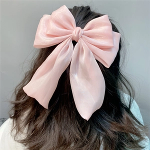Detail of pink pearlescent organza bow hair clip with long ribbons on wavy hair