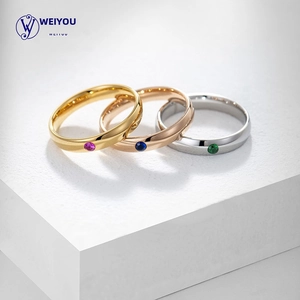 Detailed view of three minimalist rings in gold, rose gold, and silver with colored stones