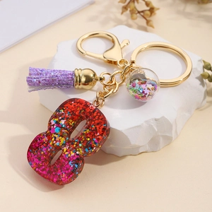 Macro detail of number 8 glitter resin keychain with purple tassel and star sequins