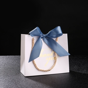 Elegant white wedding favor gift bag with golden Thank You text and blue ribbon bow