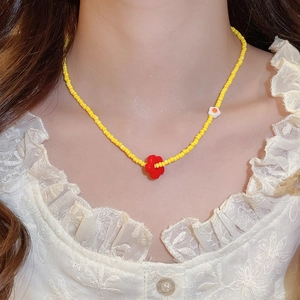 Macro shot of yellow beaded necklace with red flower pendant on lace collar dress