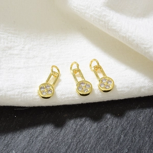 Macro view of gold flower mini pendants with micro-inlaid cubic zirconia on fabric