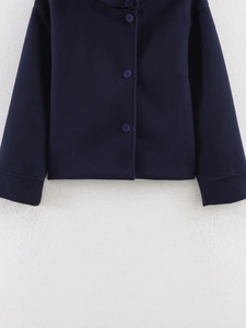 Detailed view of dark blue wool blend coat featuring round decorative buttons and fabric texture