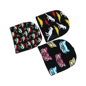 Three warm knit beanies with festive dinosaur and cat prints on black background
