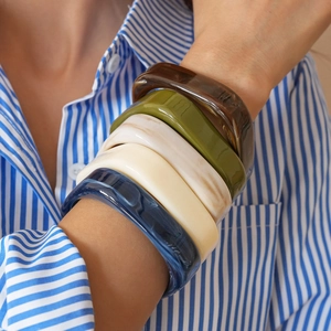 Close-up of resin square bangles with marble textures worn over a striped shirt