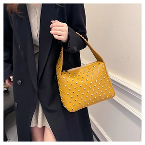 Close-up of a yellow rivet tote bag featuring silver metallic studs and leather texture