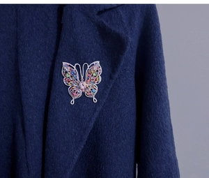 Gros plan d'une broche papillon vintage avec cristaux colorés sur un revers de manteau