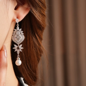 Detail showing leaf-shaped crystals and heart element with a white pearl pendant on the ear