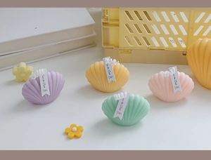 Macro shot of seashell-shaped scented candles in pastel purple, yellow, green, and pink