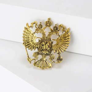 Detailed close-up of antique gold eagle totem brooch with intricate metallic relief