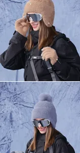Close-up of warm plush winter beanie with earflaps and touchscreen gloves in snow