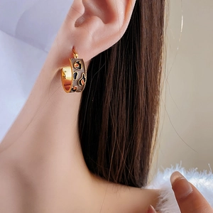 Detail of vintage gold plated C-shaped hoop earring with leopard print enamel on model