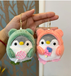 Close-up of plush penguin keychains with hoodies holding lollipop and popsicle charms