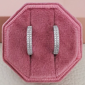 Macro shot of silver zircon studded hoop earrings in a pink velvet jewelry box