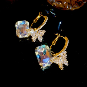 Detailed close-up of golden butterfly earrings with large square zircon and pave diamonds