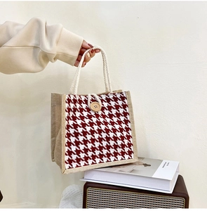Close-up of red houndstooth canvas tote bag with wooden button and rope handle