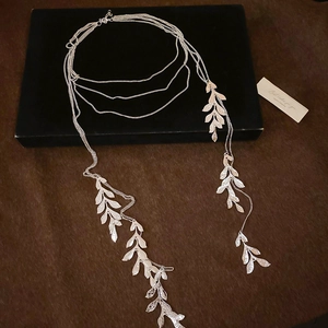 Detail view of silver multi-layer leaf tassel necklace on a black jewelry box display