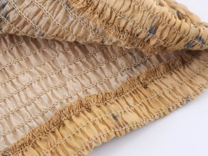 Detail of ochre pleated fabric with navy print and elastic smocking texture
